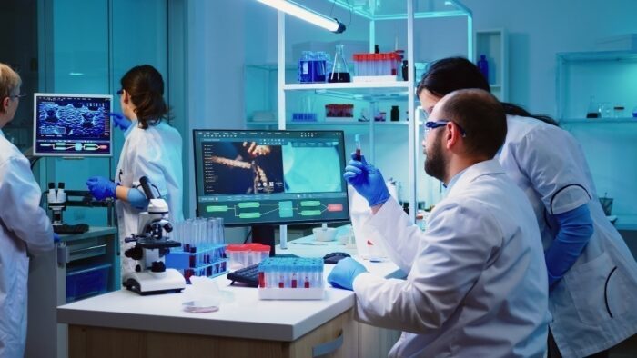 microbiologist doctor taking blood sample tube from rack with machines analysis lab background