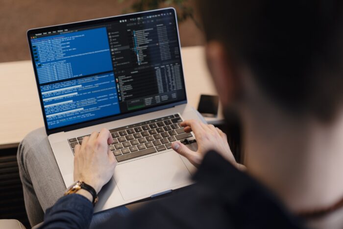 close up man writing code laptop