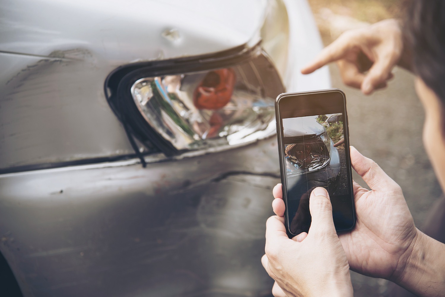 a man taking a photo of a damaged car to claim via his insurance mobile app