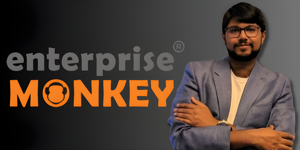 Enterprise Monkey logo with a confident man in blazer standing beside it, reflecting the company’s branding in digital transformation.